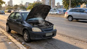 Carro parado no acostamento com o capô aberto e vapor saindo do motor superaquecido
